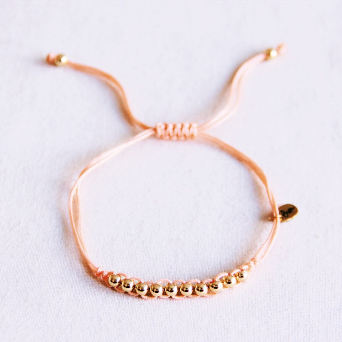 Satin bracelet with gold-colored beads - peach