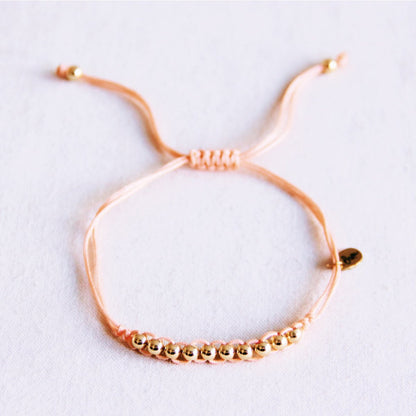 Satin bracelet with gold-colored beads - peach