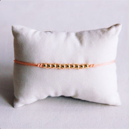 Satin bracelet with gold-colored beads - peach