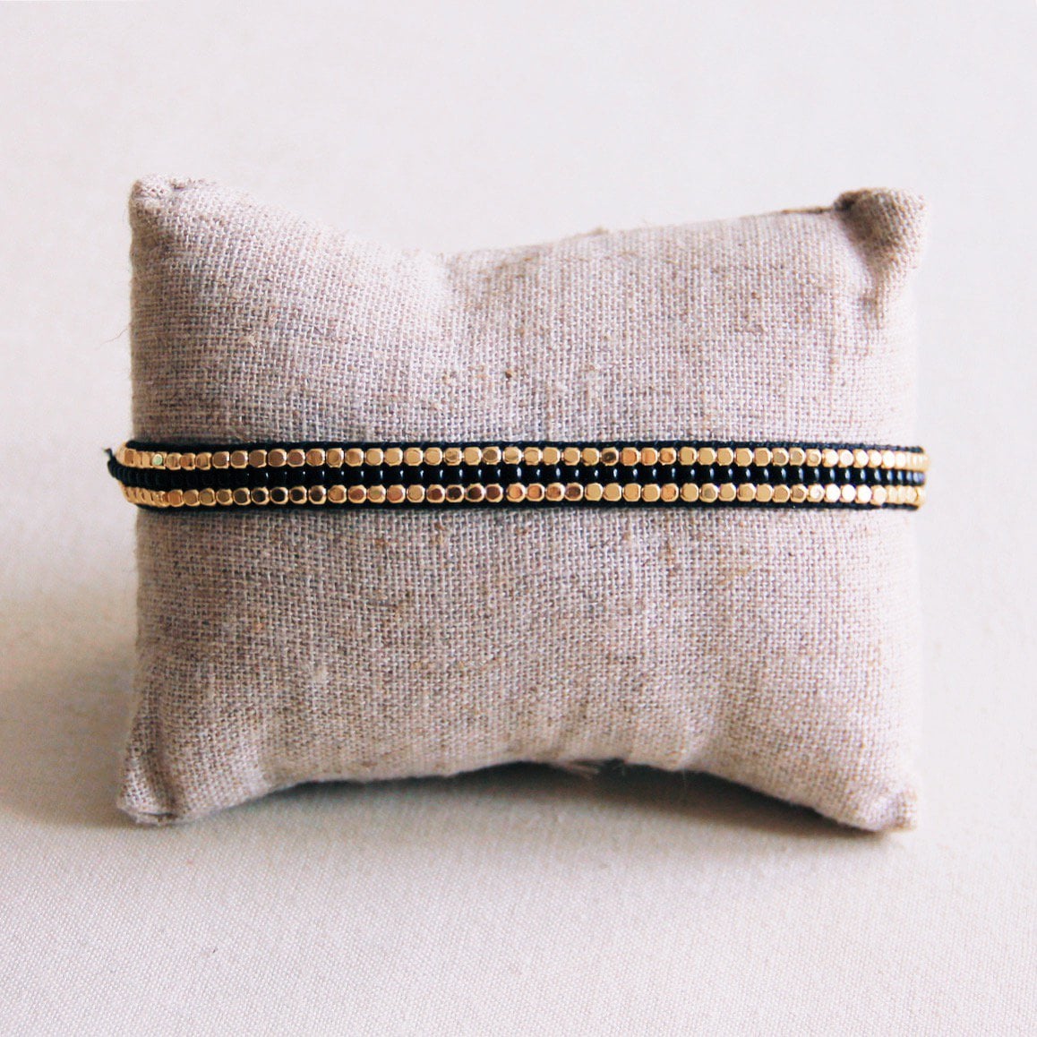 Woven bracelet of black gemstones and gold-colored blocks