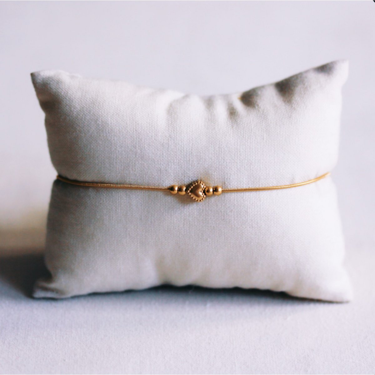 Delicate snake chain bracelet with a detailed heart charm and small beads – gold